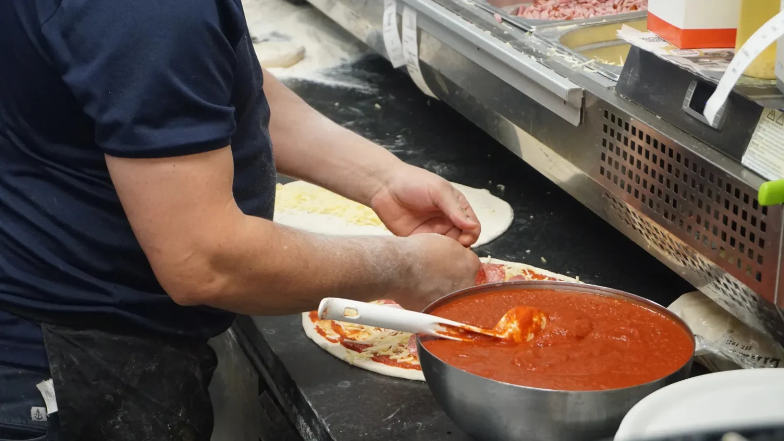 Pizzabagare som tillagar pizza i köket